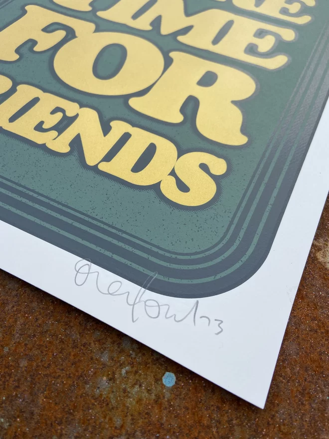 green leather looking screen print with gold letters that says “make more time for friends”