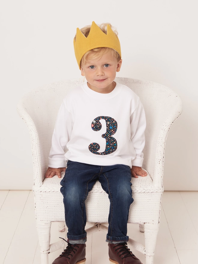 3 year old boy sitting wearing a white long sleeve t-shirt with a number 3 sewn on in Liberty Fizz Pop Black print 