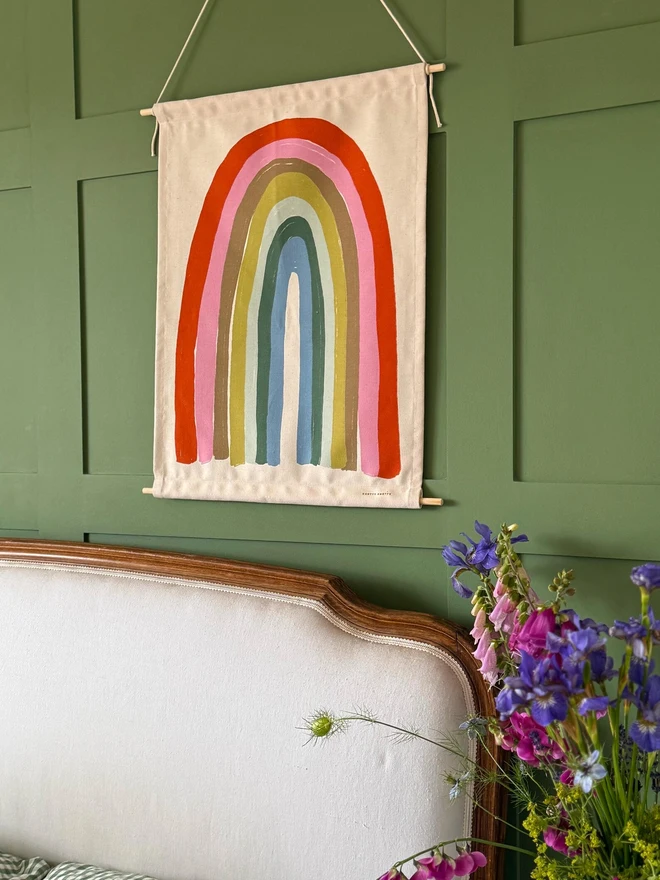 Cotton Pastel Rainbow Fabric Banner, against a green wall. 