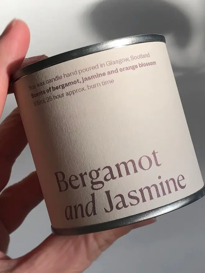 Bergamot & Jasmine Candle, held in a hand against a white background. 