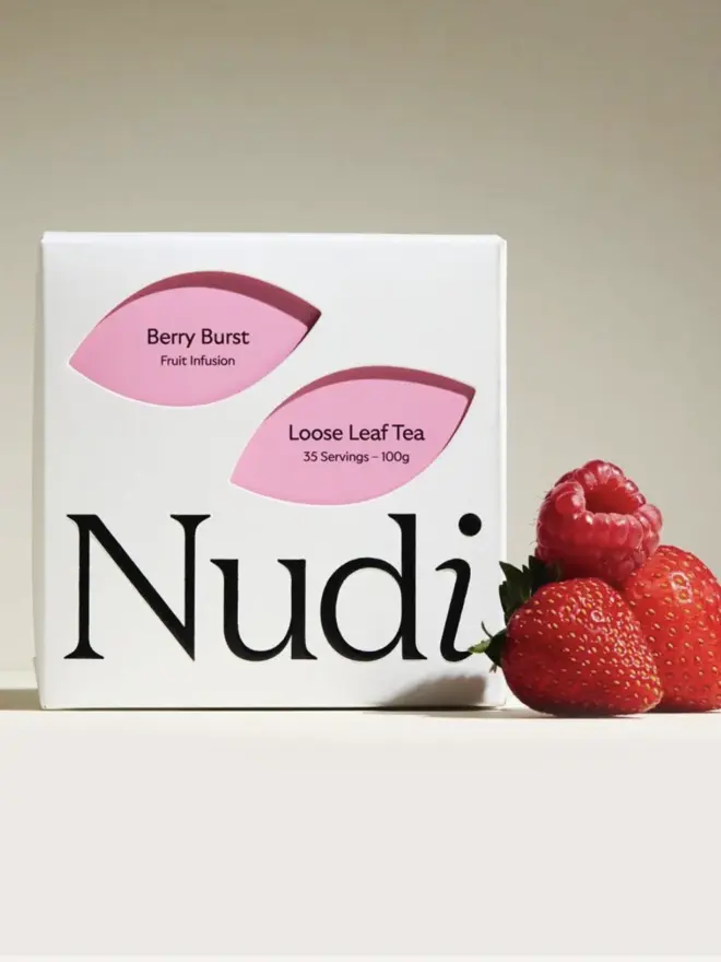 berry burst tea in white box with pink leaf design next to red berries