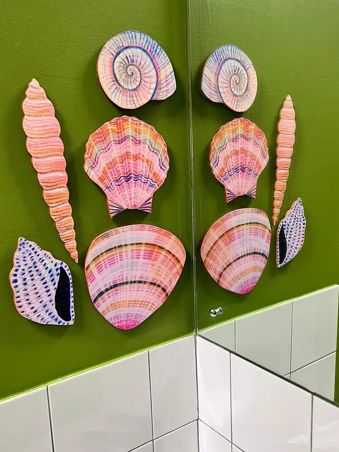 wooden shell wall art decoration. illustrated shells on a green bathroom wall.