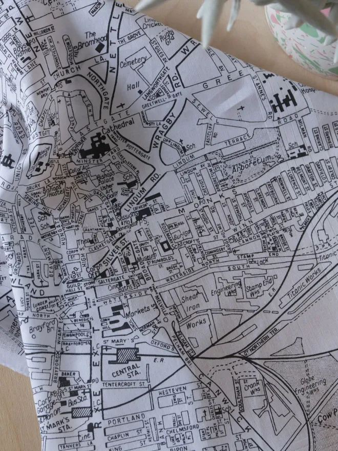 Mr.PS Lincoln Map Handkerchief screenprinted in grey, shown in detail on a wooden table