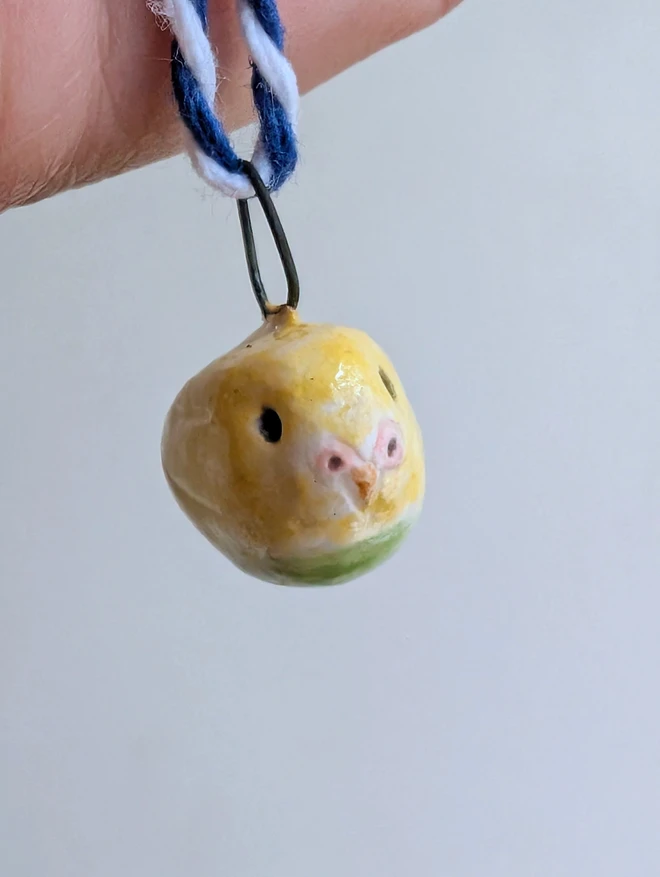 pottery budgie hanging bell decoration with a miniature yellow ceramic bird