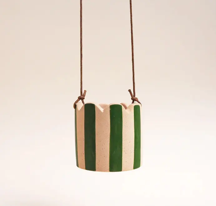 Small Stripy Hanging Plant Pot. Peach pink   ceramic pot decorated with vertical stripes against a plain light background.