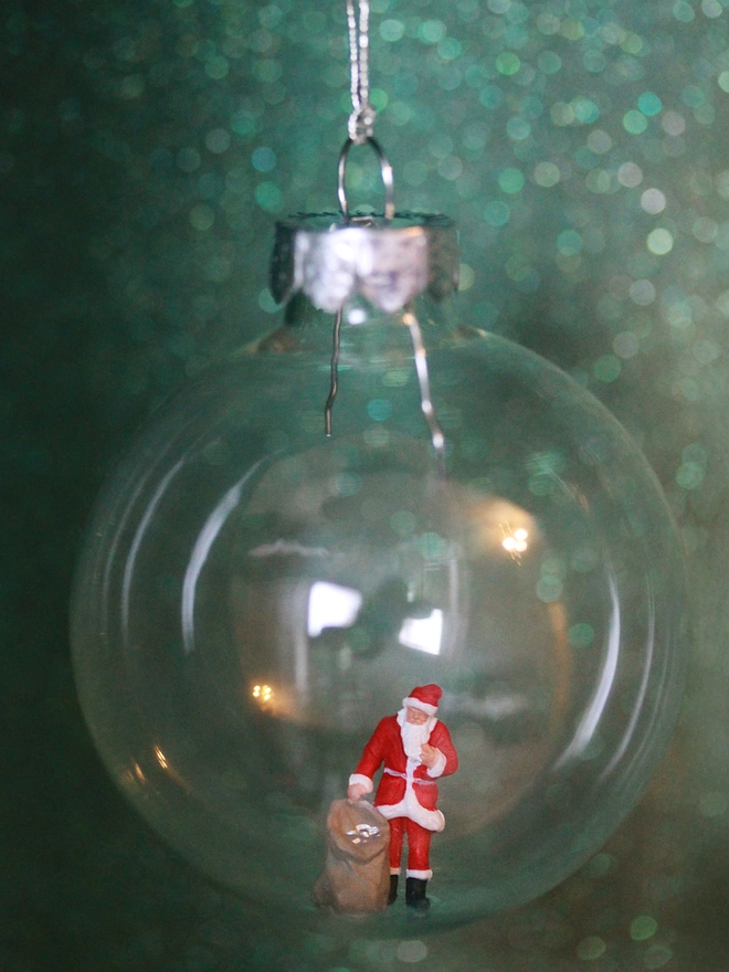 Miniature figure of Santa Claus with a bag of gifts  in a glass Christmas bauble  