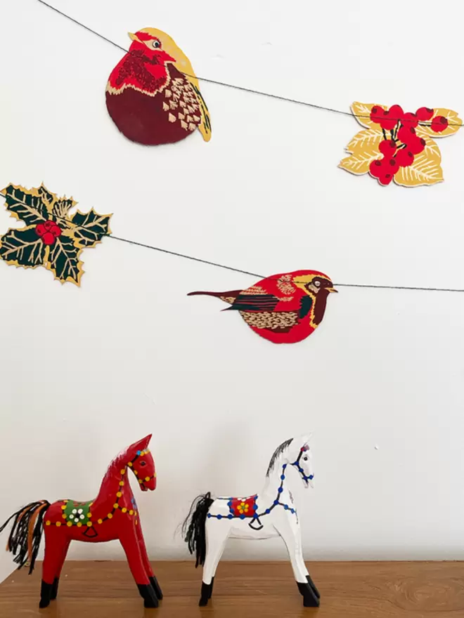 red and gold garland hanging over 2 wooden horses