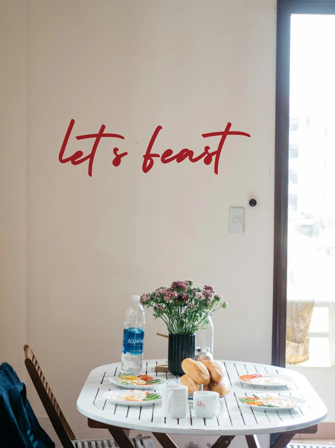 lets feast wall sticker in red above a dinning table