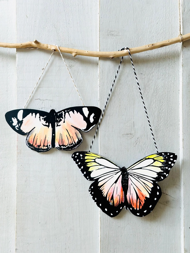 Hand Painted Butterfly Colourful Linocut Hanging Decoration In Orange Peach and black two hang next to each other off a stick to show a display option