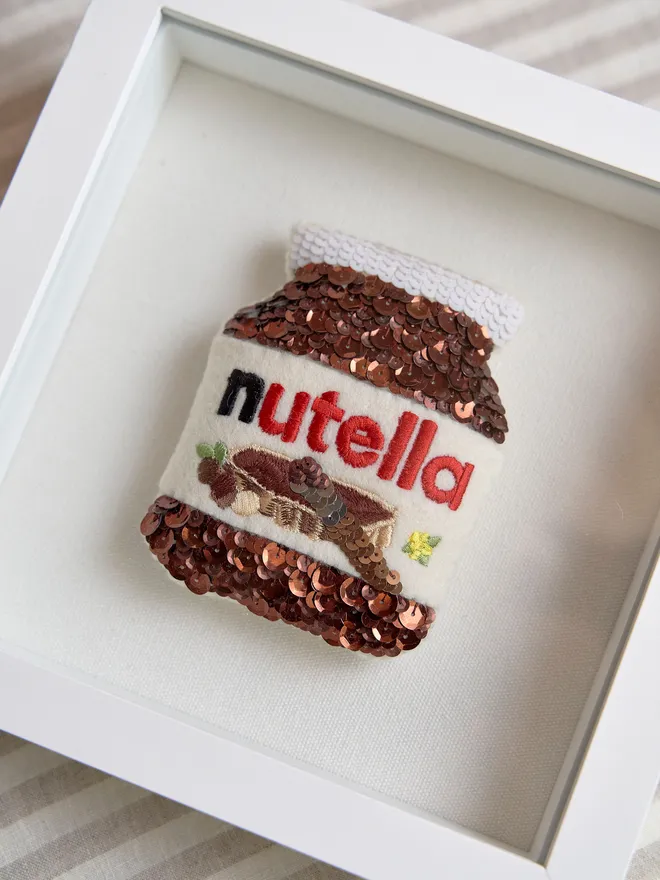 Custom sequin artwork. Nutella jar made from sequins in a white frame. 