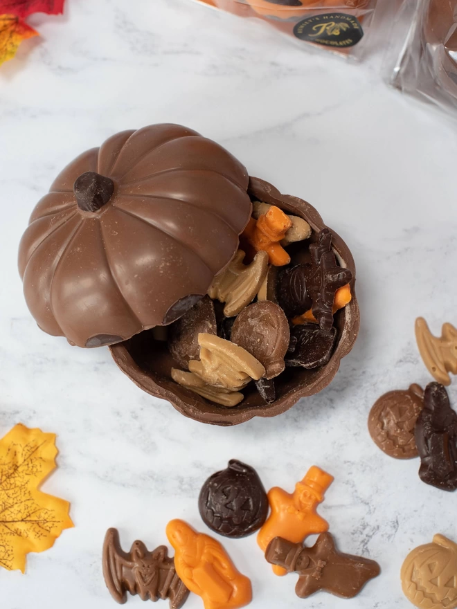 Open chocolate pumpkin with assorted halloween chocolate shapes