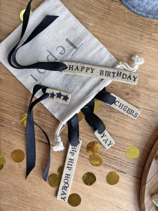 a selection of celebration themed ceramic tags, poking out of a drawstring bag 