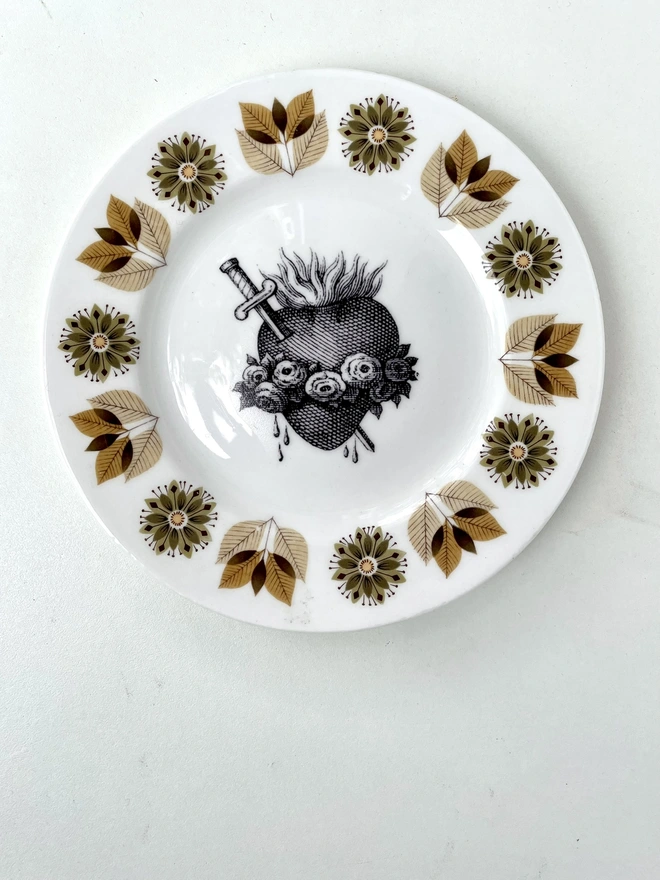 a vintage plate with an ornate border and in the centre is an old illustration of a beautiful sacred heart
