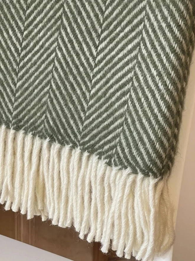 Lambswool olive throw with white tassels.