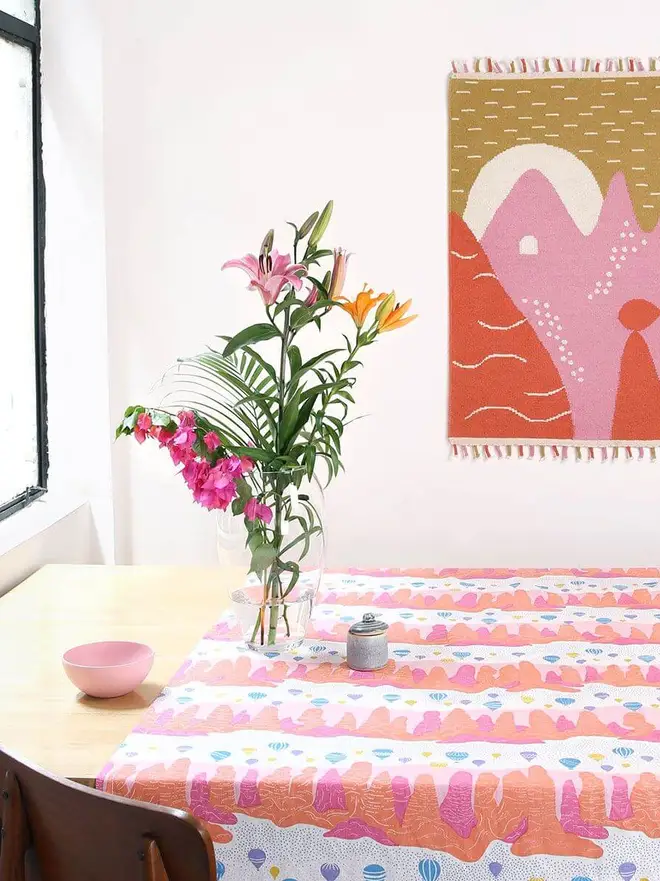 Landscape Flatweave Rug, a colourful rug hanging in a kitchen. It is accompanied by dining accessories. 