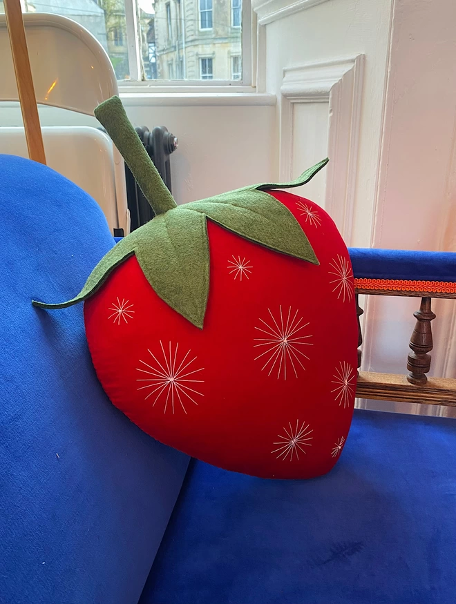 Red strawberry cushion on blue chair