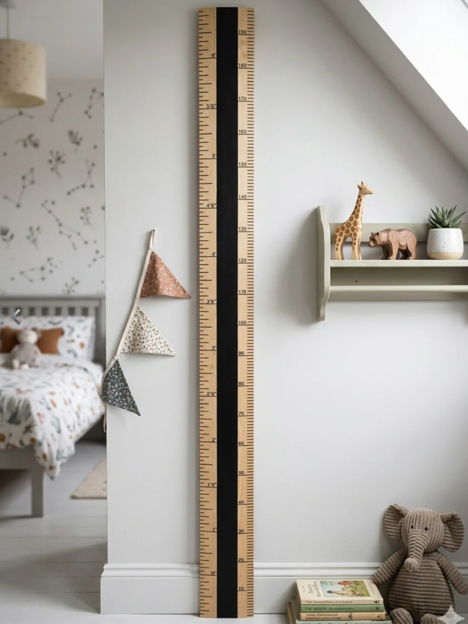 Blackboard Ruler Height Chart. A wooden and black ruler leaning against a child’s wall.