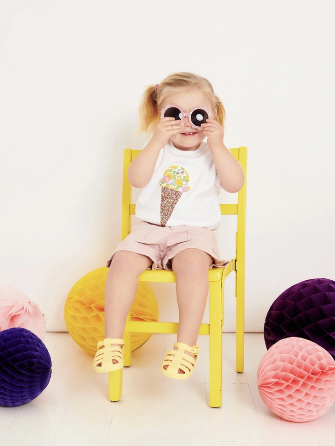 little girl wearing a white t-shirt with a floral ice cream sewn on the front