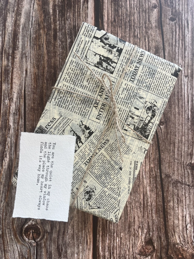 gift wrapping in newspaper vintage print tissue paper tied with brown twine thread with a typewritten hand made gift note typed on cotton rag paper