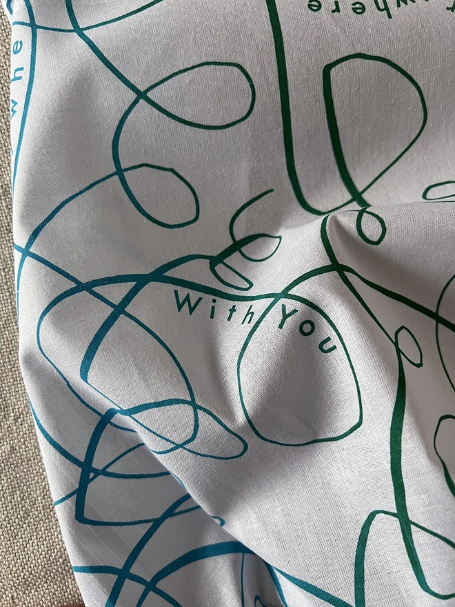 Detail of a Mr.PS Anywhere Everywhere Together With You printed cotton handkerchief on a linen tablecloth