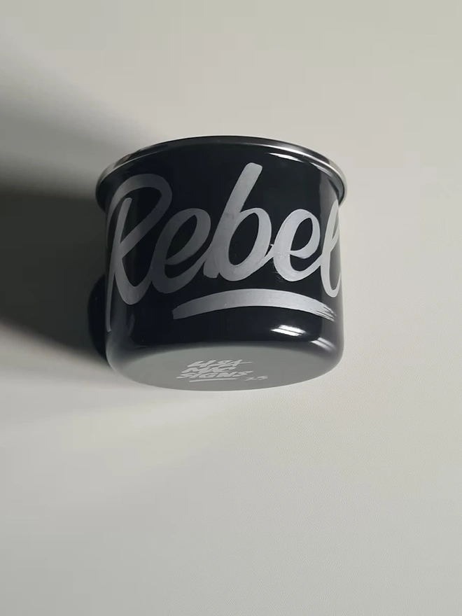 'Rebel' Enamel Mug, a colourful mug sitting on a white surface. 