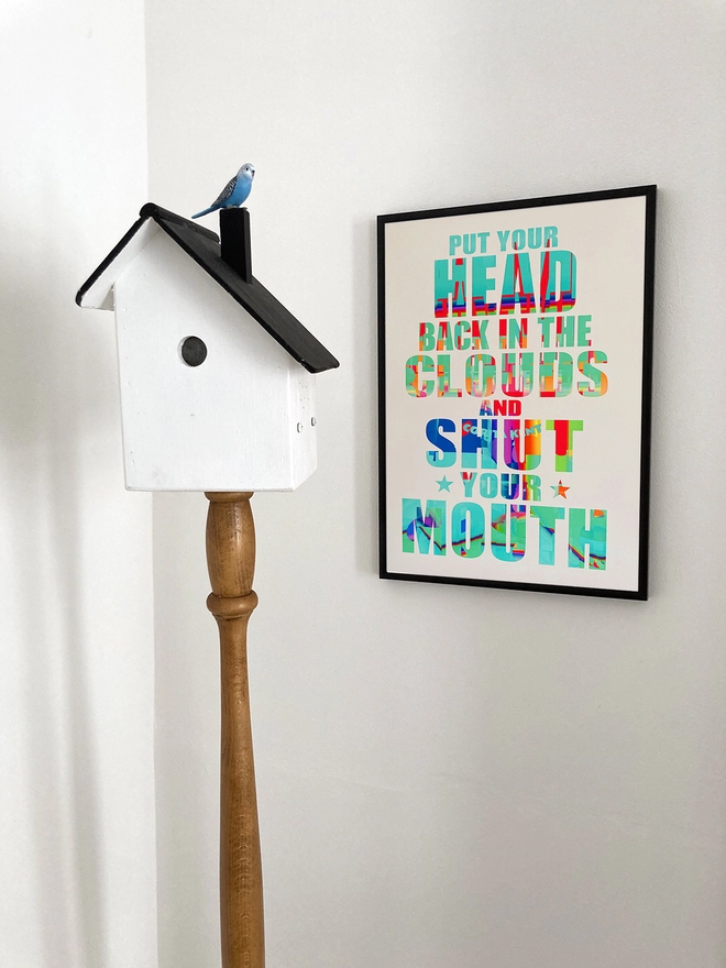 Framed multicoloured typographic print of a Julian Cope song, “put your head back in the clouds and shut your mouth”. The print han