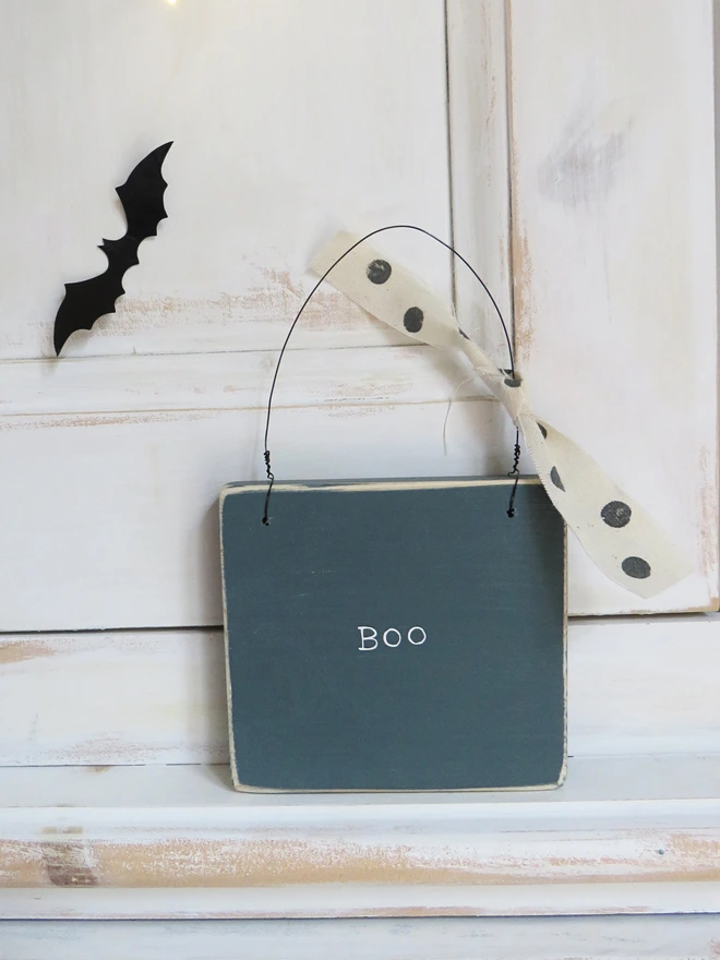 inky blue hand painted wooden sign with boo message and spotty ribbon detail