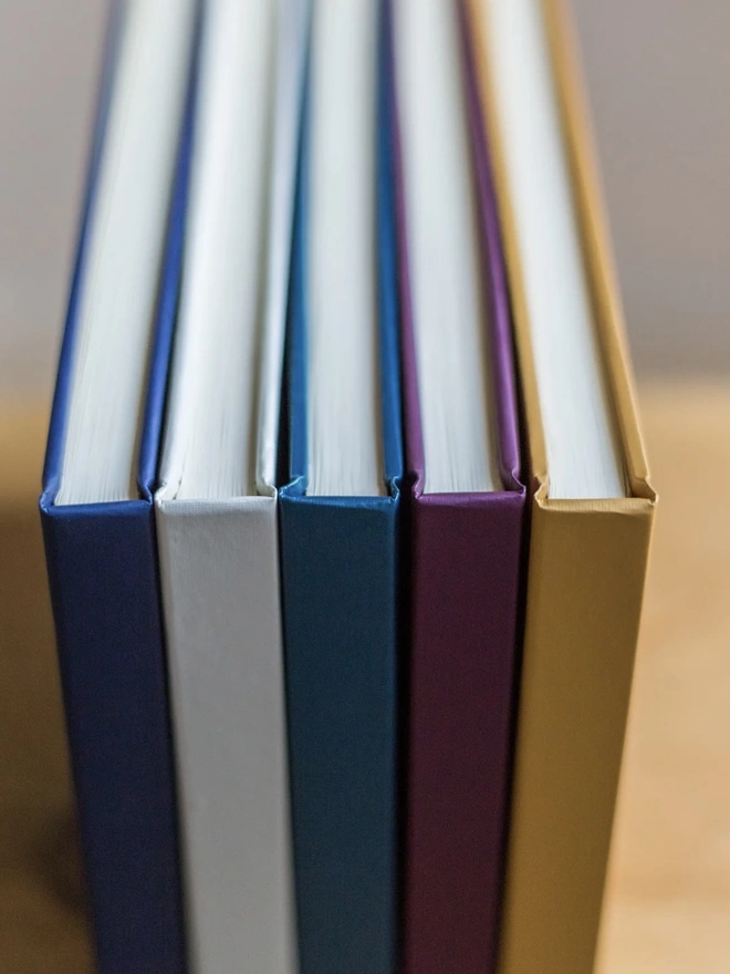 Personalised Luxury Guest Books For A Home stacked on a wooden surface. 