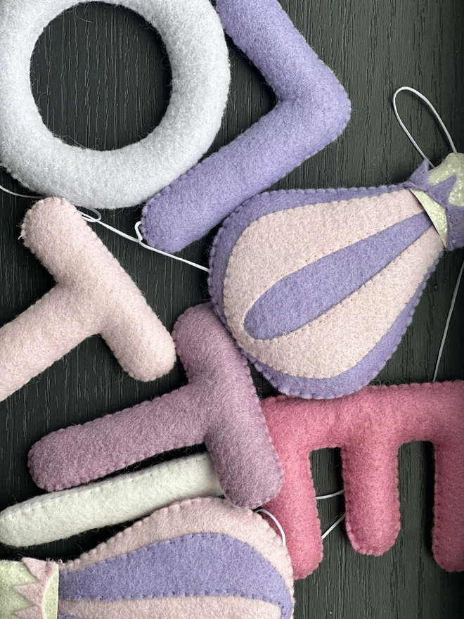 Personalised Name Icon Garland, a child’s name banner hanging from a white shelf, nursery decoration, baby gift
