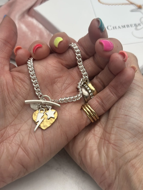 large gold heart charm and silver mini bolt and star charms on sterling silver chunky curb charm bracelet with silver t bar fastener. gift box and pouch