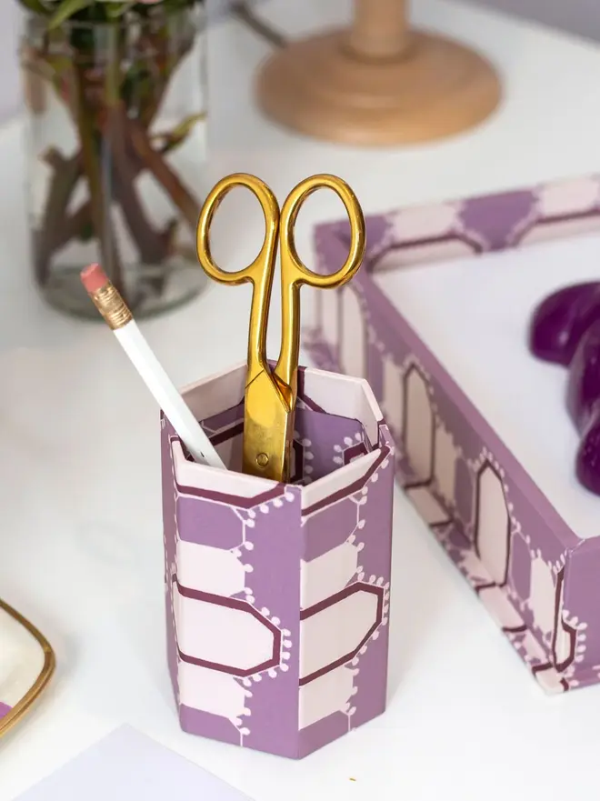 Tijan Hexagonal Brush Pot, a colourful patterned pencil pot sitting on a white surface accompanied by some desk accessories. 