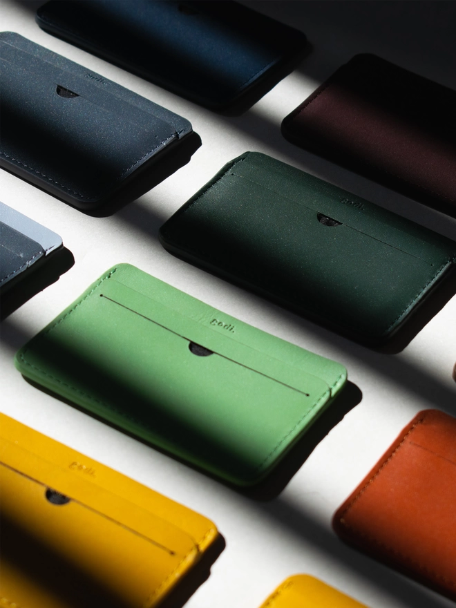 Assortment of cardholders laid out with the amber yellow, sea green, dark green included