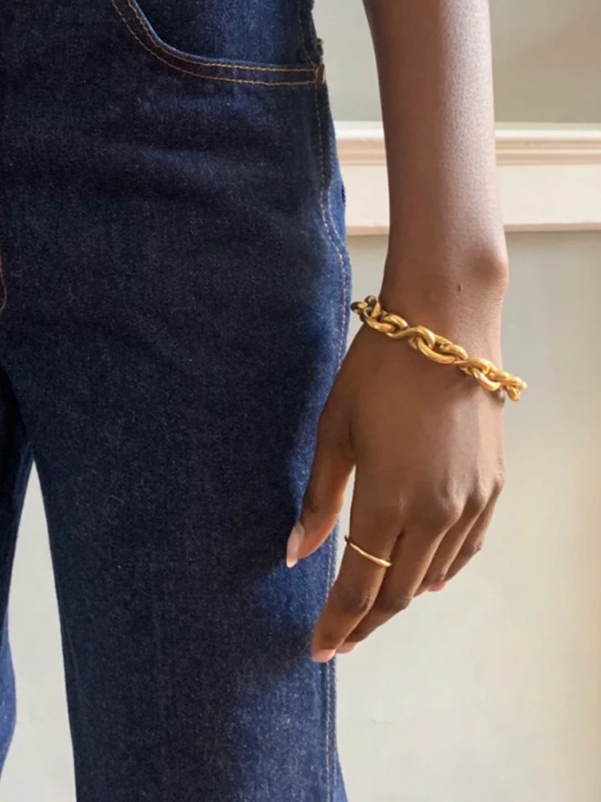 chunky gold chain bracelet worn on a black model with a delicate gold ring