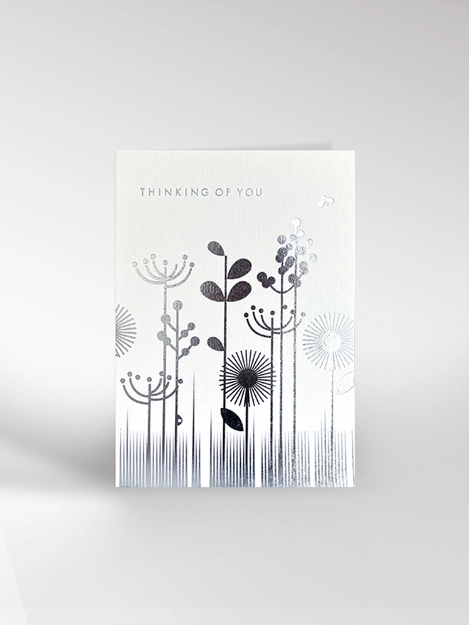 Thinking Of You card featuring a meadow of flowers and grasses in a graphic style and foiled in silver