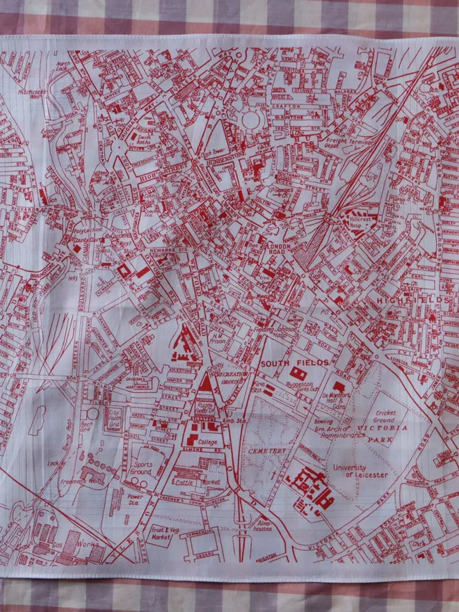 A Mr.PS Leicester map handkerchief, printed in red, laid on a gingham tablecloth