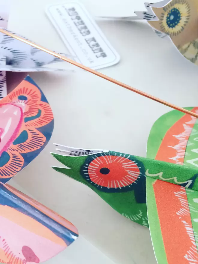 Detail of colourful paper birds lying on a white background