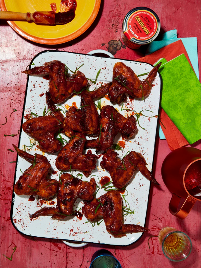 korean gochujang chilli paste. chicken wings marinated in korean chilli paste photographed on a white platter.