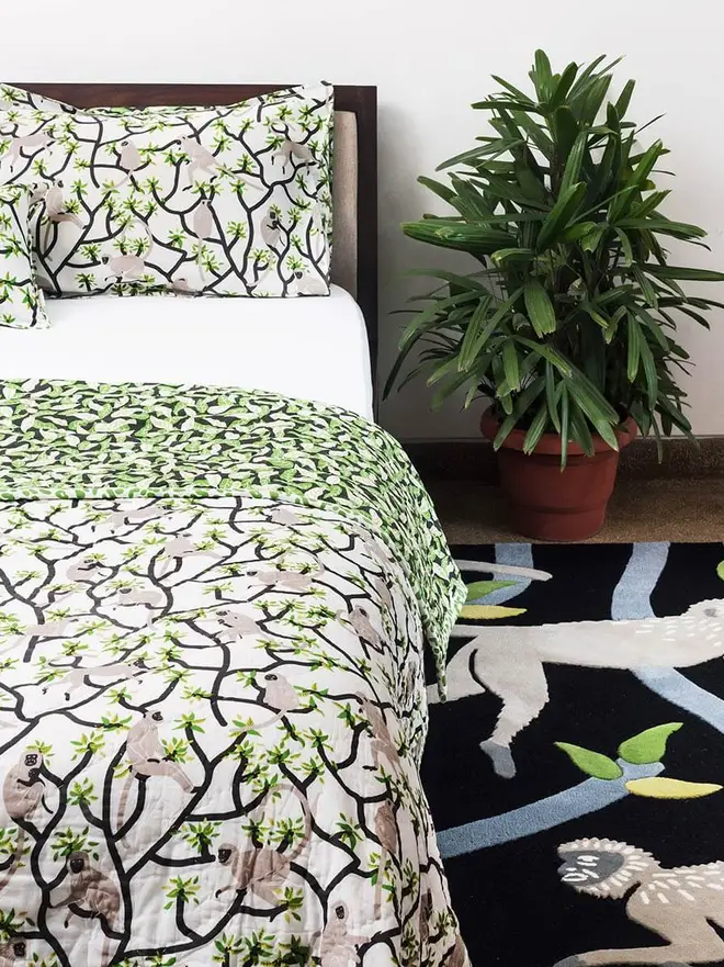 Langur Hand Tufted Rug, a monkey design rug sitting in a bedroom. It is accompanied by some bedroom accessories. 