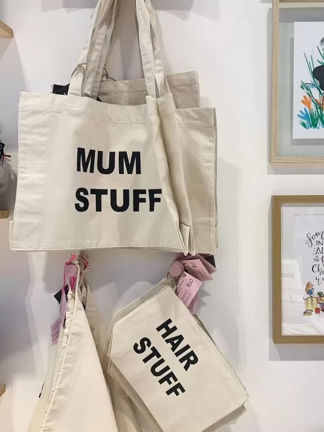 mum stuff natural canvas tote bag hanging on a wall to showcase how they look