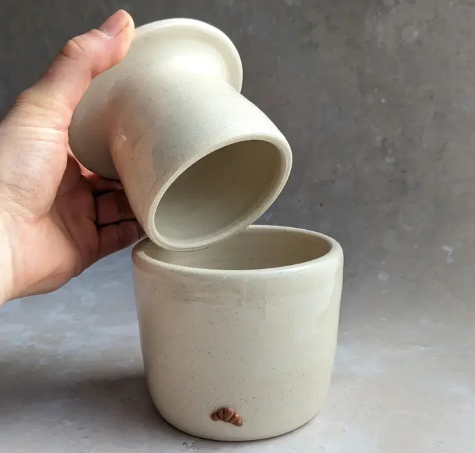 Croissant Butter Crock in vanilla bean glaze with a small croissant design on the front, set against a clean white marble background.