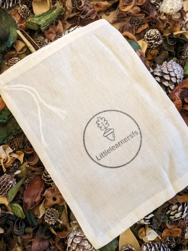 white gift bag displayed on leaves and forest floor.