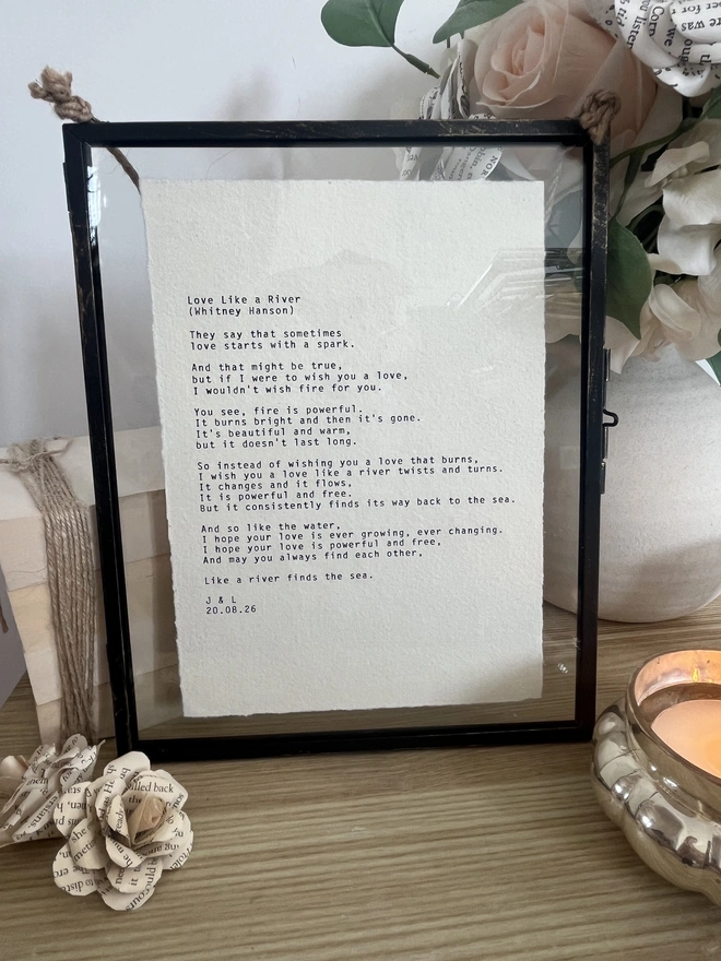 Framed typewriter print hand typed with an antique typewriter onto cotton rag handmade deckled paper. It is displayed in a black hanging rustic frame with gold brush detailing and decorated with real pressed dried flowers.