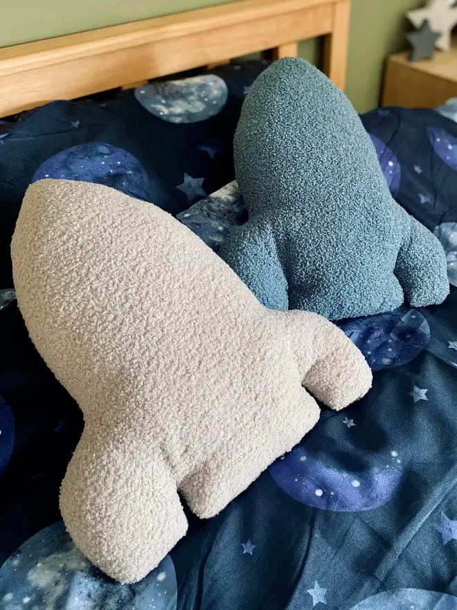 boucle rocket pillow. blue and grey rocket cushions on a bed with space-themed sheets.