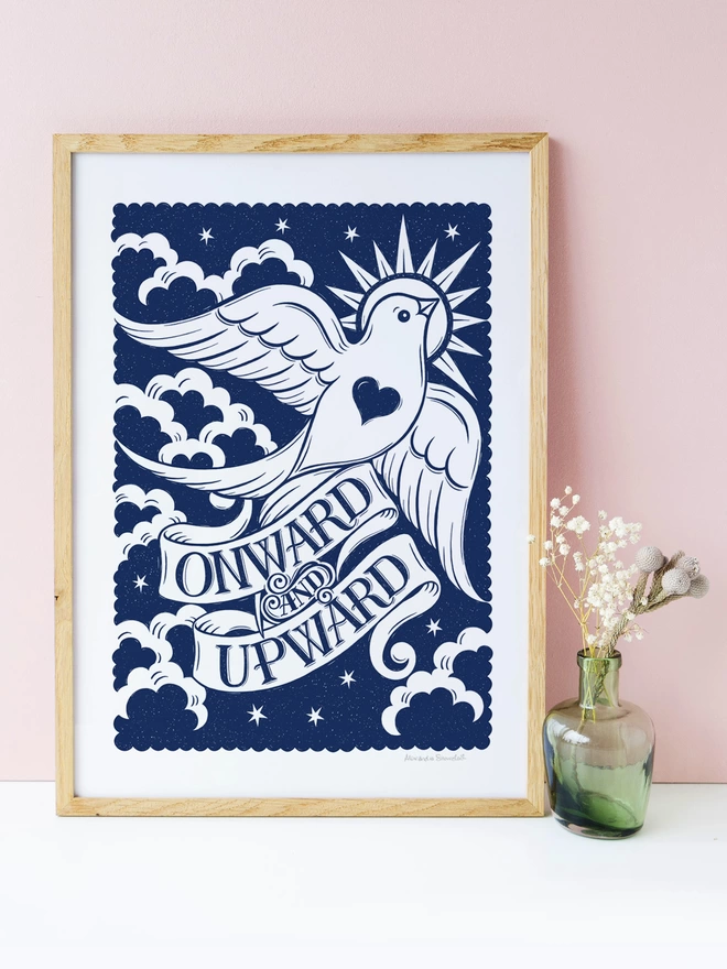 blue and white onward and upward print with white dove in a wood frame on pink background