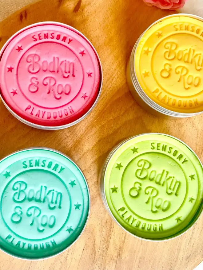 fairy sensory play dough sensory set. four tubs of coloured dough in pink, yellow, blue and green.