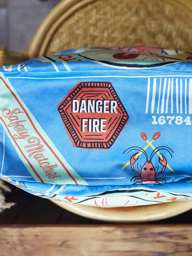 Lobster Matchbox Cushion, a decorated lobster cushion sitting on an arm chair. 