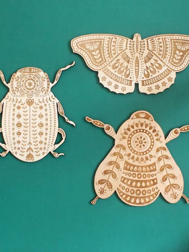 Wooden Folk Art Butterfly Hanging Decoration, wooden insect decoration hanging on a green wall. 