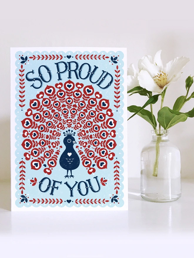 proud of you peacock card in red white and blue with flower