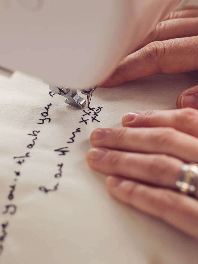 hands moving fabric to create sewn words using freehand machine embroidery