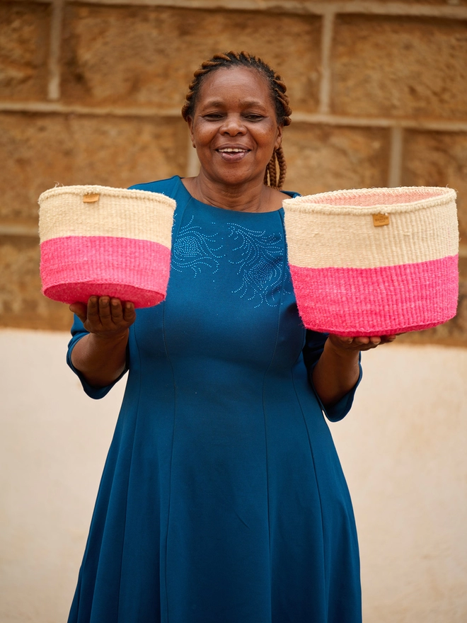 weaver holding pink colour block baskets